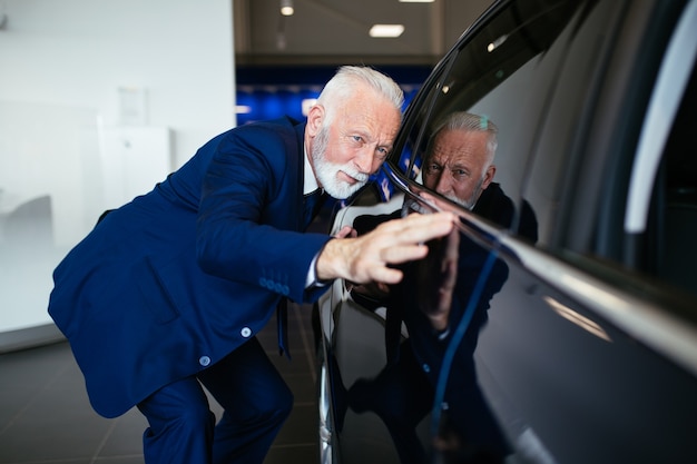 Uomo anziano che sceglie una nuova auto presso l'autosalone.