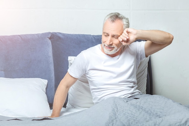 Uomo anziano che si sveglia sul letto al mattino