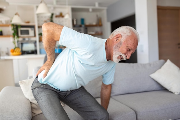 Uomo anziano che si tocca la schiena che soffre di mal di schiena sciatica stile di vita sedentario concetto problemi di salute della colonna vertebrale assicurazione sanitaria