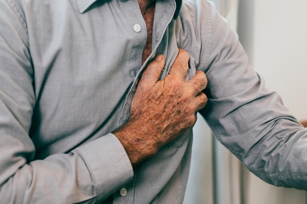 Uomo anziano che tiene la mano sul petto e soffre di problemi cardiaci a casa