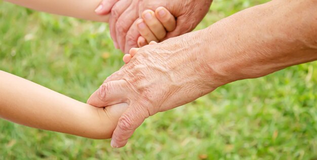 Uomo anziano che tiene le mani del bambino messa a fuoco selettivaPeople