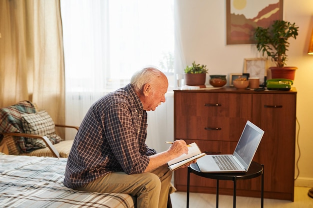 Uomo anziano che usa il computer portatile a casa