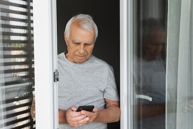 Uomo anziano che utilizza lo smartphone a casa