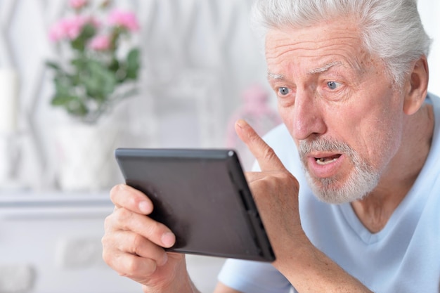 Uomo anziano che utilizza tablet a casa
