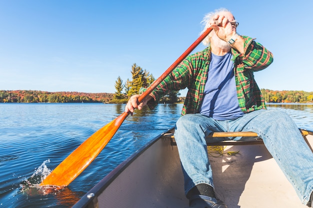 Uomo anziano con canoa canottaggio in una giornata di sole