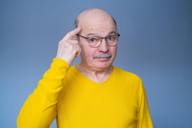 Uomo anziano con gli occhiali che tiene le dita sulla tempia