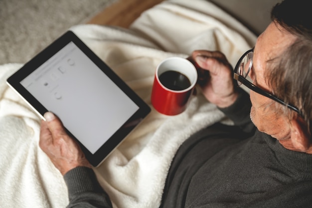 Uomo anziano con gli occhiali utilizzando un tablet