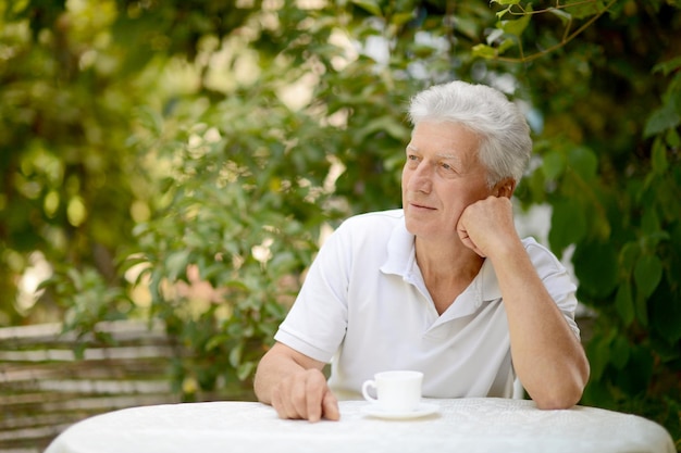 Uomo anziano con una tazza di caffè al caffè estivo