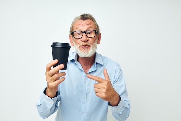 Uomo anziano dai capelli grigi con un bicchiere nero in mano un drink isolato sullo sfondo