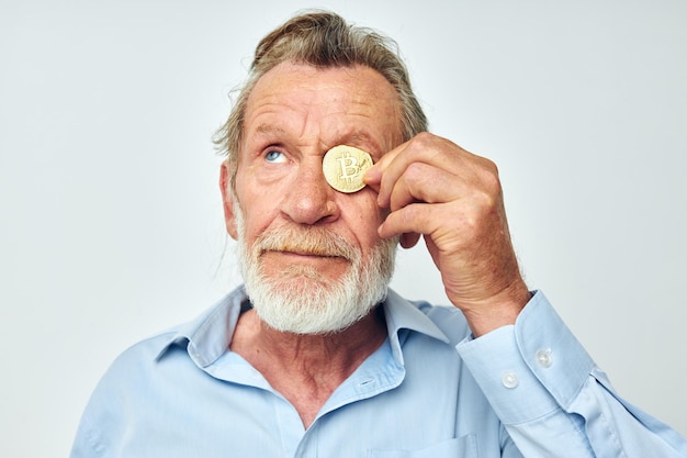 Uomo anziano dai capelli grigi in una camicia blu bitcoin sullo sfondo del viso isolato