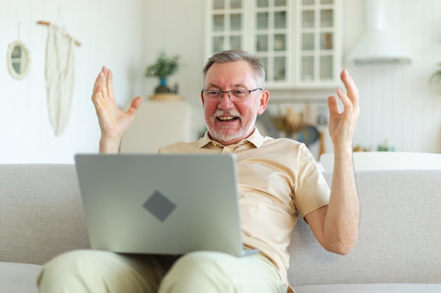 Uomo anziano di mezza età eccitato vincitore euforico nonno più maturo che guarda il portatile che legge