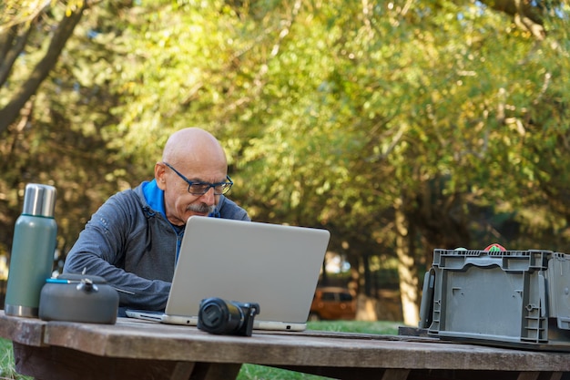 Uomo anziano felice che usa il computer in natura