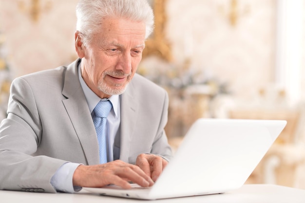 Uomo anziano felice che usa il laptop a casa