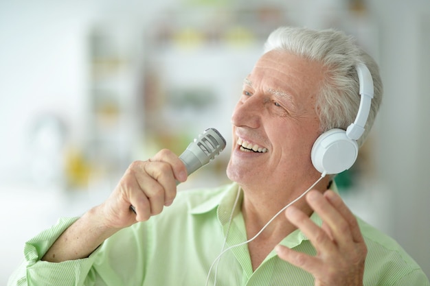 Uomo anziano in cuffia che canta nel microfono