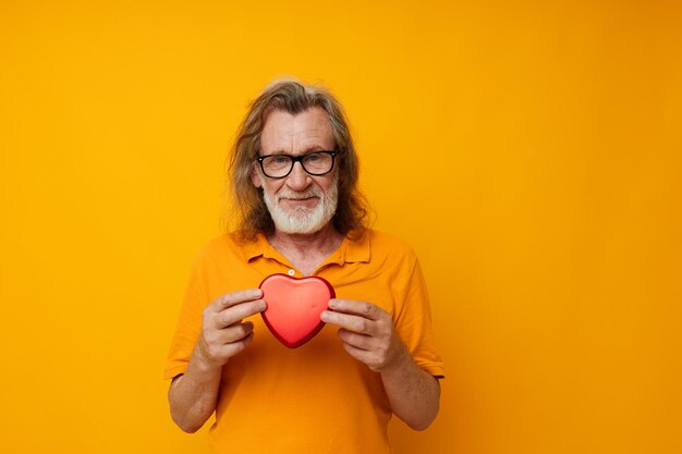 Uomo anziano in occhiali gialli con una barba grigia cuore rosso colpo monocromatico