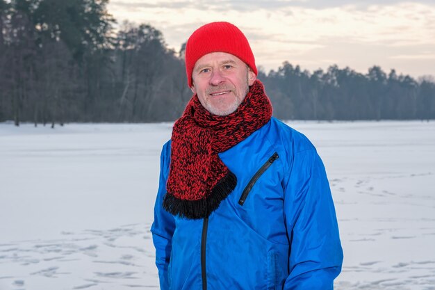 Uomo anziano in piedi nella foresta invernale che riposa dopo l'esercizio