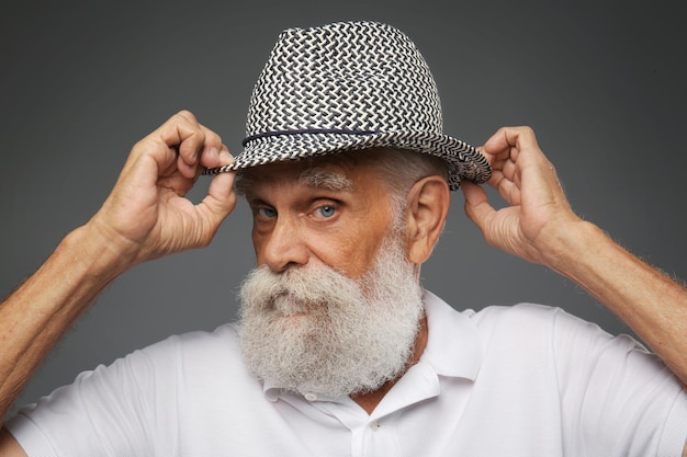 Uomo anziano in un cappello su sfondo grigio