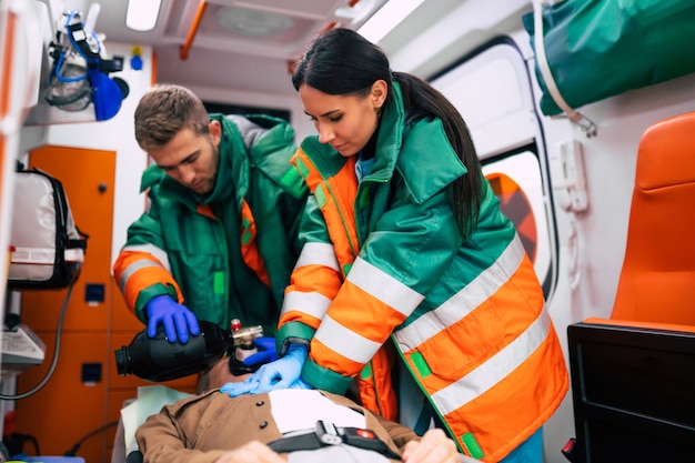 Uomo anziano incosciente e paramedici che lavorano nell'ambulanza