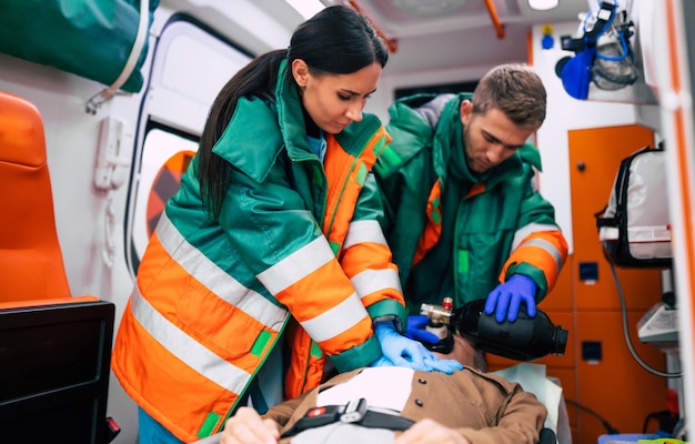 Uomo anziano incosciente e paramedici che lavorano nell'ambulanza