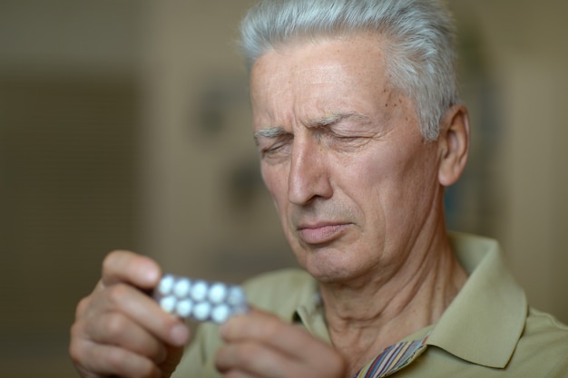 Uomo anziano malato con pillole in mano