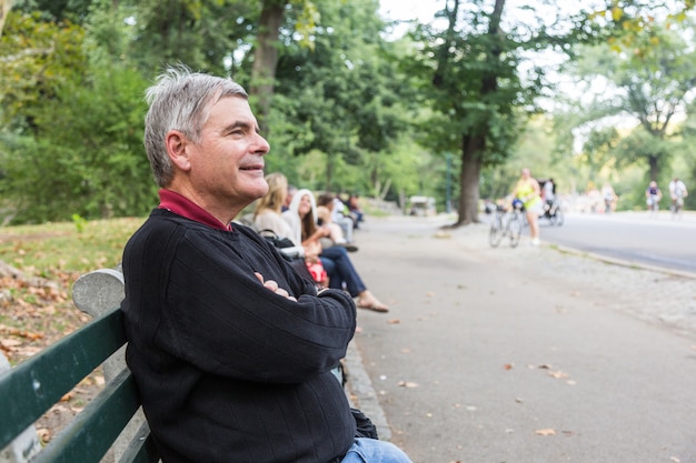 Uomo anziano pensionato al parco, seduto su una panchina