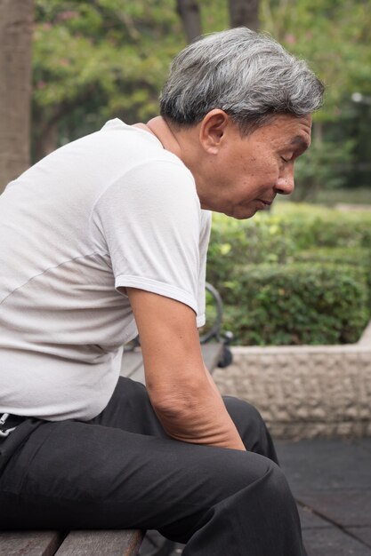 Uomo anziano pensionato triste che si siede nel parco pubblico