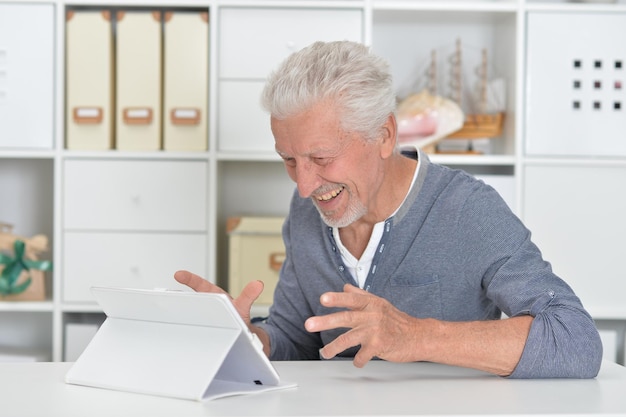 Uomo anziano premuroso con tablet a casa