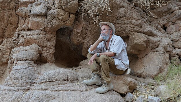 Uomo anziano seduto su una roccia nel deserto