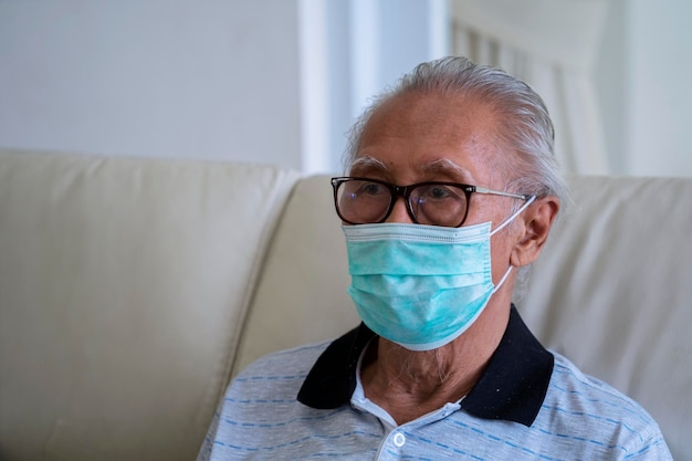 Uomo anziano seduto sul divano con maschera medica