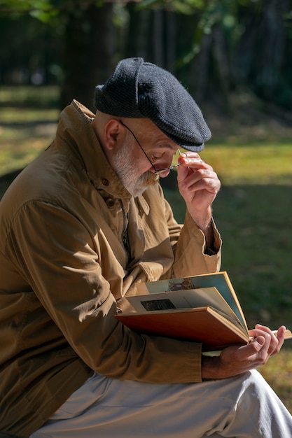 Uomo anziano seduto sulla panchina a leggere un libro