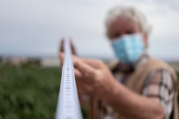 Uomo anziano sfocato all'aperto sulla terrazza che tiene un metro per la distanza sociale ai tempi del coronavirus