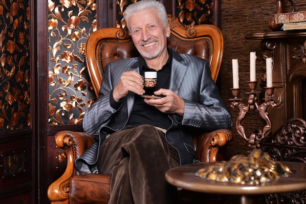 Uomo anziano sorridente che beve caffè a casa