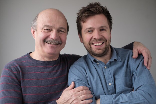 Uomo anziano sorridente con suo figlio adulto che sorride avendo umore positivo