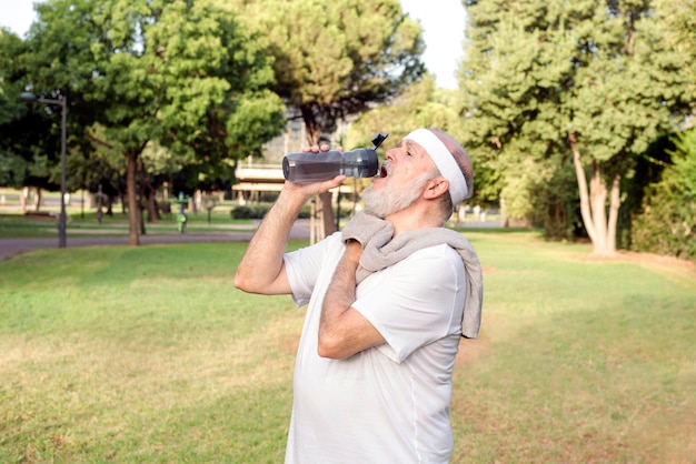 Uomo anziano stanco che beve acqua e si prende una pausa dopo un duro esercizio