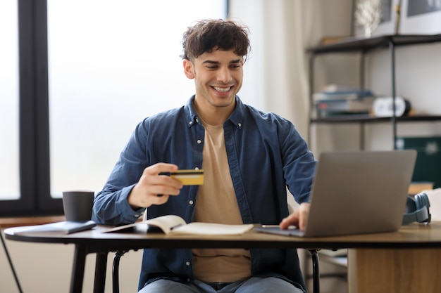 Uomo arabo che fa shopping utilizzando il computer portatile e la carta di credito in ufficio