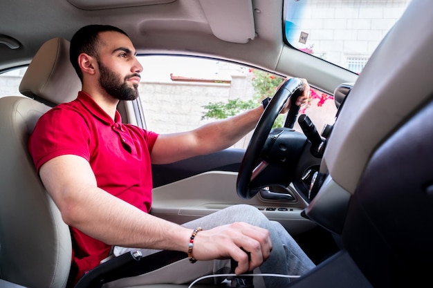 Uomo arabo che guida la sua auto con un sorriso e si sente sicuro