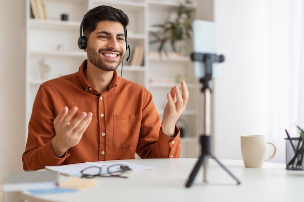 Uomo arabo che ha videochiamata utilizzando il cellulare sul treppiede