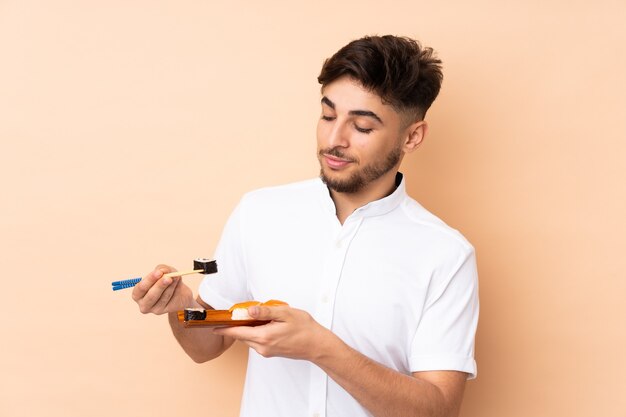 Uomo arabo che mangia sushi isolato sul beige