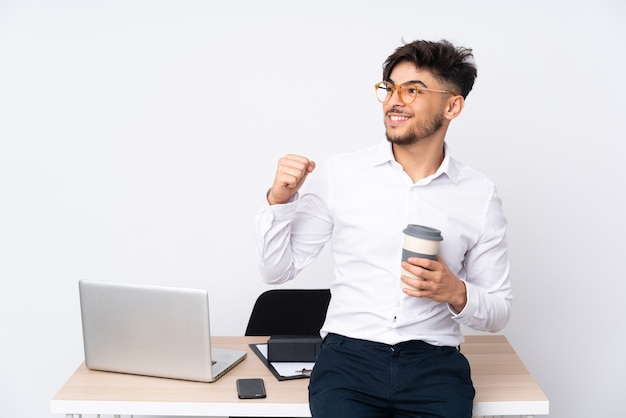 Uomo arabo in un ufficio isolato su sfondo bianco che celebra una vittoria