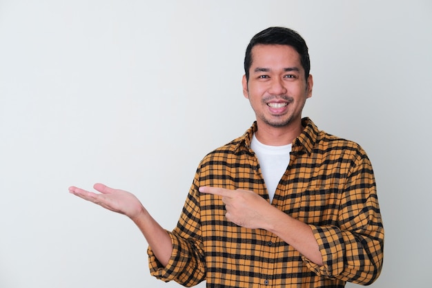 Uomo asiatico adulto che indica il palmo della mano con la faccia sorridente