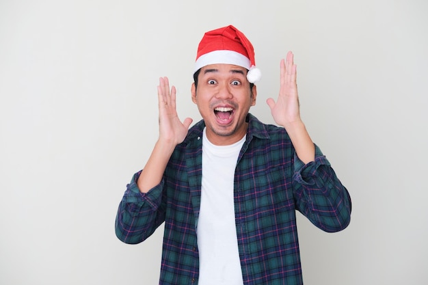 Uomo asiatico adulto che indossa il cappello di Natale che mostra gesto sorpreso