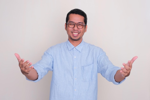 Uomo asiatico adulto che sorride eccitato mentre apre le braccia per il saluto