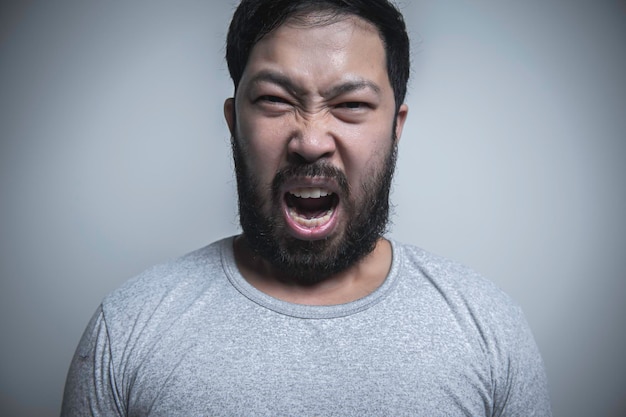 Uomo asiatico bello arrabbiato su sfondo bianco Ritratto di giovane concetto maschile di stress