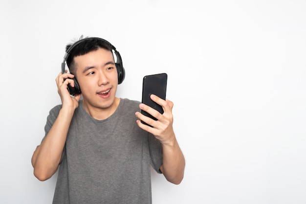 Uomo asiatico che ascolta la musica dallo smartphone e che passa in rassegna Internet su fondo bianco