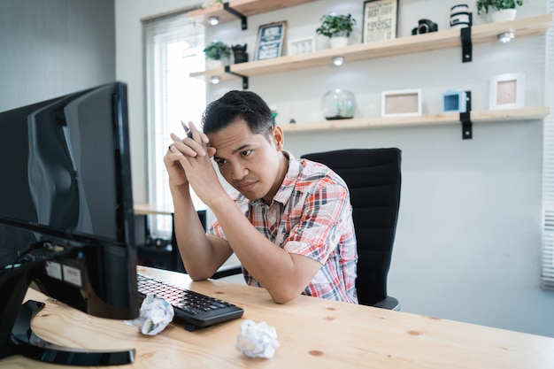 Uomo asiatico che aspetta qualcosa che esamina pc