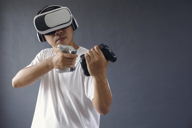 Uomo asiatico che gioca seriamente utilizzando google e console VR su sfondo grigio scuro Copia s