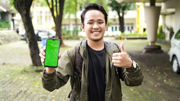 Uomo asiatico che indossa il cellulare con schermo verde con gesto ok