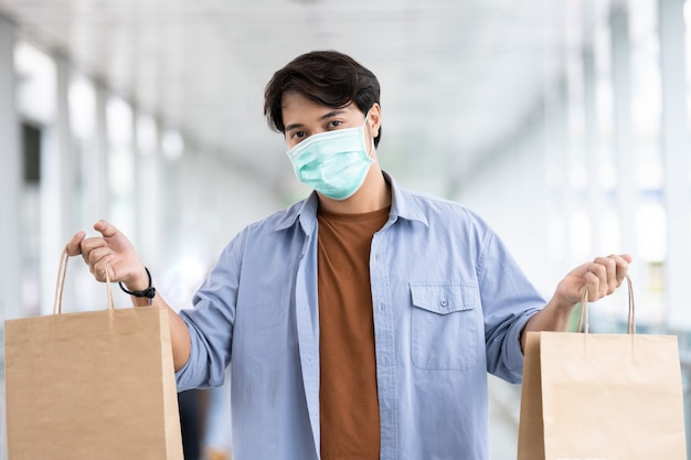 Uomo asiatico che indossa il sacchetto della spesa protettivo della tenuta della maschera di protezione