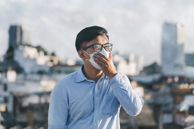 Uomo asiatico che indossa la maschera facciale per proteggere la polvere PM 25 e il problema dell'inquinamento atmosferico polvere smog COVID19