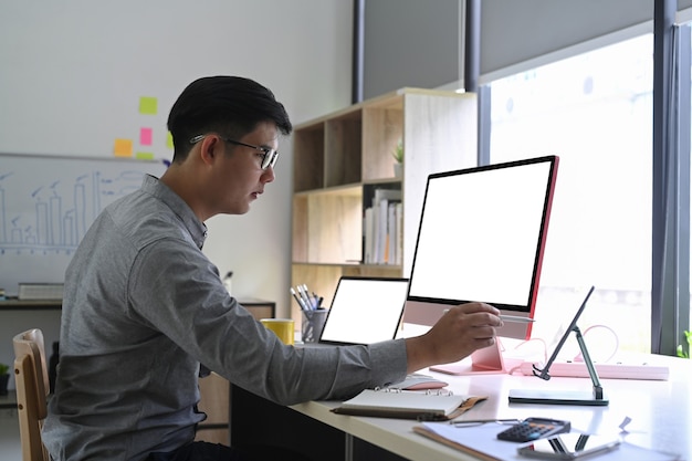 Uomo asiatico che lavora con gadget moderni in ufficio a casa.